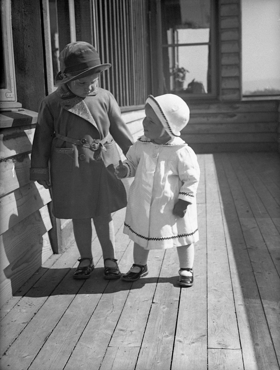 Søstrene Siri og Guri Arentz står på verandaen i søndagsklær, P.T. Mallings vei 4. Fotografert april 1932.