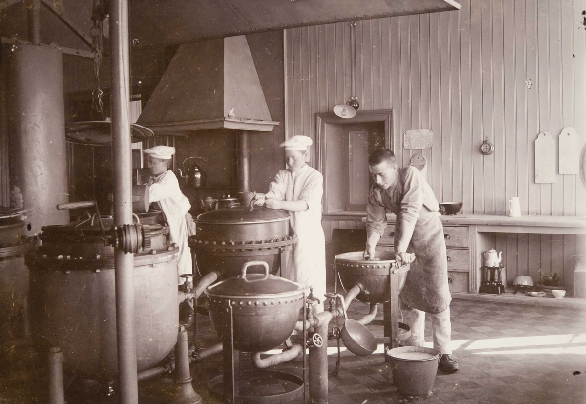 Fra kjøkkenet på Bastøy skolehjem, Bastøya, ca. 1903. Tre elever har kjøkkentjeneste.