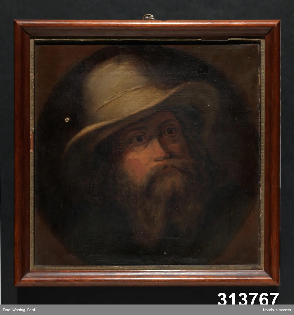 Porträtt av en man med skägg och slokhatt. 