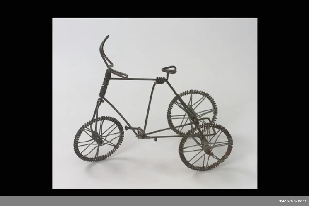 Inventering Sesam 1996-1999:
L 16 cm
B 11 cm
H 13 cm
Trehjulig cykel, leksak. Helt och hållet tillverkad av ståltråd, s.k. luffararbete. Rörliga hjul och pedaler. 
Inlånad till luffarutställningen 1984.
Bilaga = beskrivning av luffare och luffararbeten
Leif Wallin jan 1998