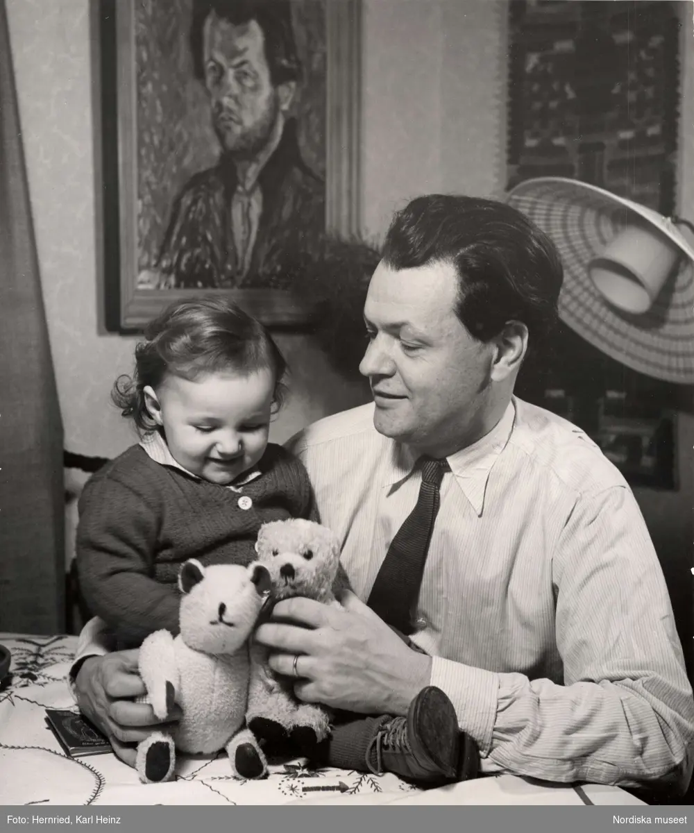 En man och ett litet barn sitter vid ett bord och leker med teddybjörnar.
