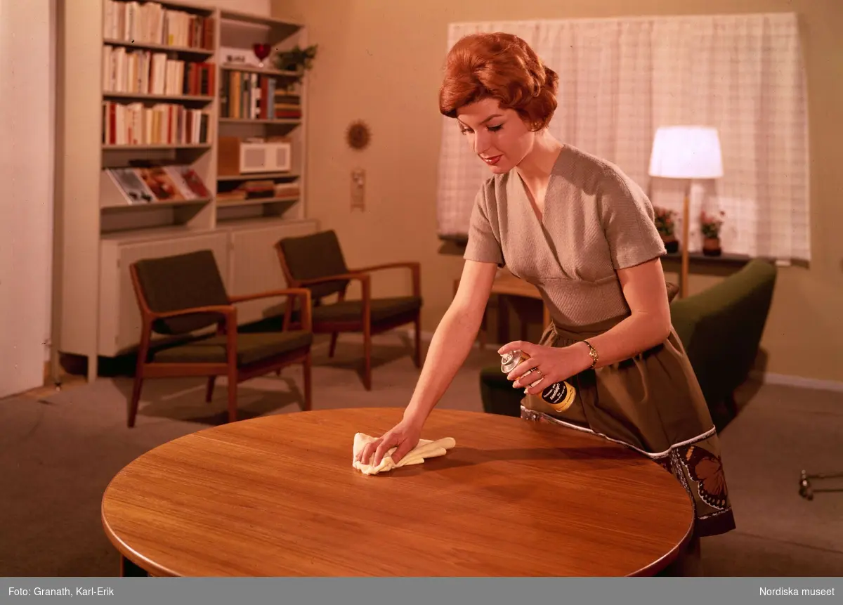 Hushåll. Kvinna rengör bord i vardagsrum.