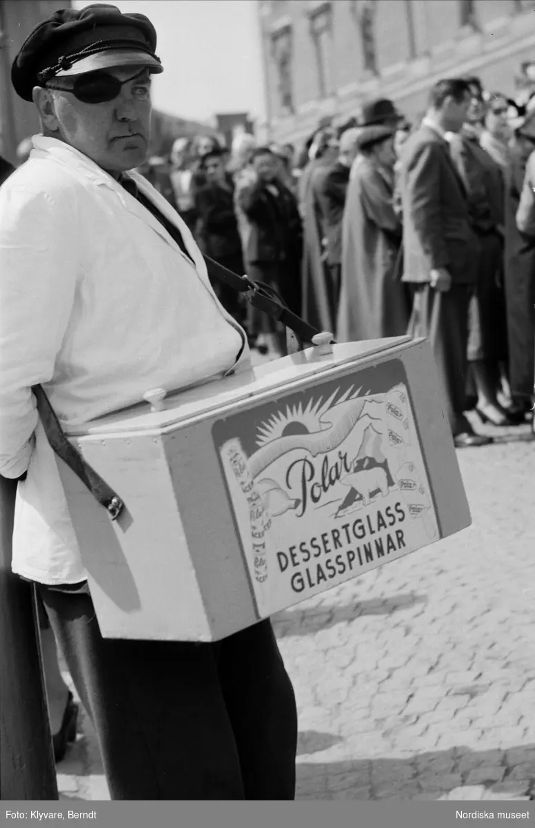 Glassförsäljare med ögonlapp och "låda på magen" vid drottning Julianas besök i Stockholm 1957.