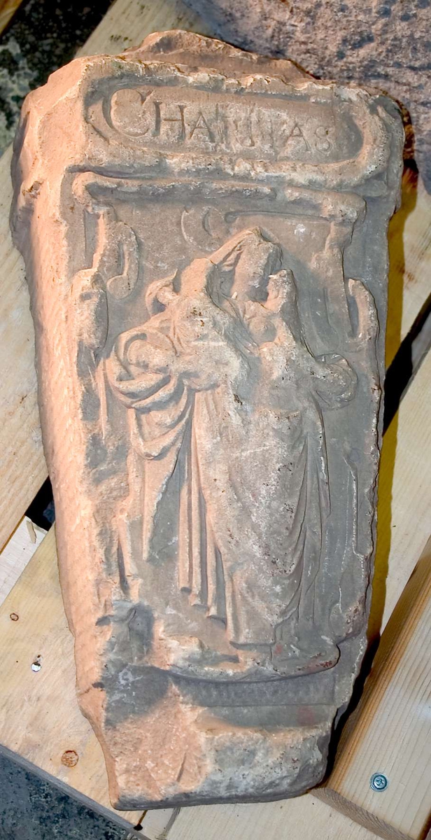 Byggnadsdetalj av sandsten, med mönster i relief. Inskription "CHARITAS" (det kristna kärleksbudskapet).