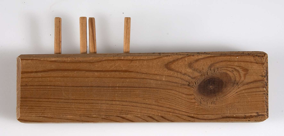Solvstock av trä. Rektangulär omålad träbit; på ena långsidan fyra pinnar, på motsatt sida hål för ytterligare fyra. På ena kortsidan skrivet med blyerts: Elsa.