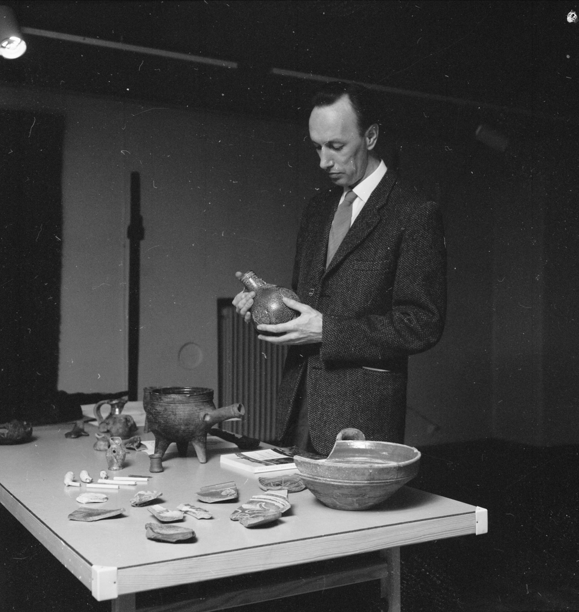 Lars Gezelius visar arkeologiska fynd som tillvaratagits vid schaktningar i kvarteret Duvan vid Smedsgränd, Uppsala 1962
