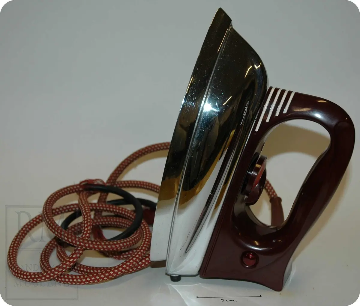 Trekantformet jern, med burgunderfarget plasthåndtak, med skive for å justere temperatur. 