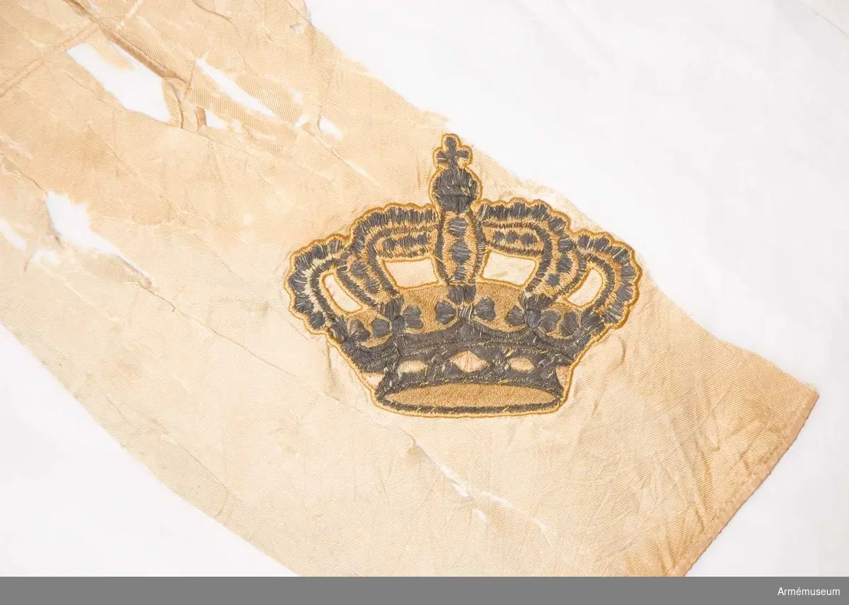 På det gulvita kyprade fansidenet sitter i mitten ett broderat monogram föreställande två motställda "C" inneslutande "XIV". Broderiet utfört i plattsöm med silke och silvertråd. Ovanför monogrammet sitter en kunglig krona utförd i plattsöm med foder i rött silke. I fanans hörn sitter snedställda kronor i brunt silke. Ett fragment av fanan på vilken en av de fyra kronorna sitter ligger löst och hoprullat tillsammans med fanan. Fanspetsen har Karl XIV Johans monogram, dock mycket ärgat. Fanstången är gulvitmålad. Kravatten, den lilla del som återstår, är uppsydd på ett bomullsband.