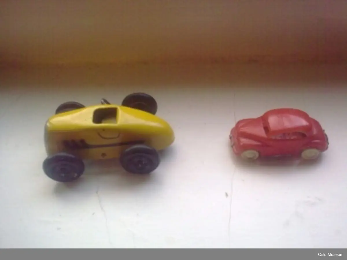A= grønn lekebil i tre utformet som personbil i typisk 1950-tallsstil
B= rød lekebil i tre utformet som personbil i typisk 1950-tallsstil. Far til giver har risset inn nummerplate og skåret ut bakvindu
C= rød lekebil i plast utformet som personbil i typisk 1950-tallsstil.
D= gul lekebil i metall utformet som sportsbil i typisk 1950-tallsstil.
