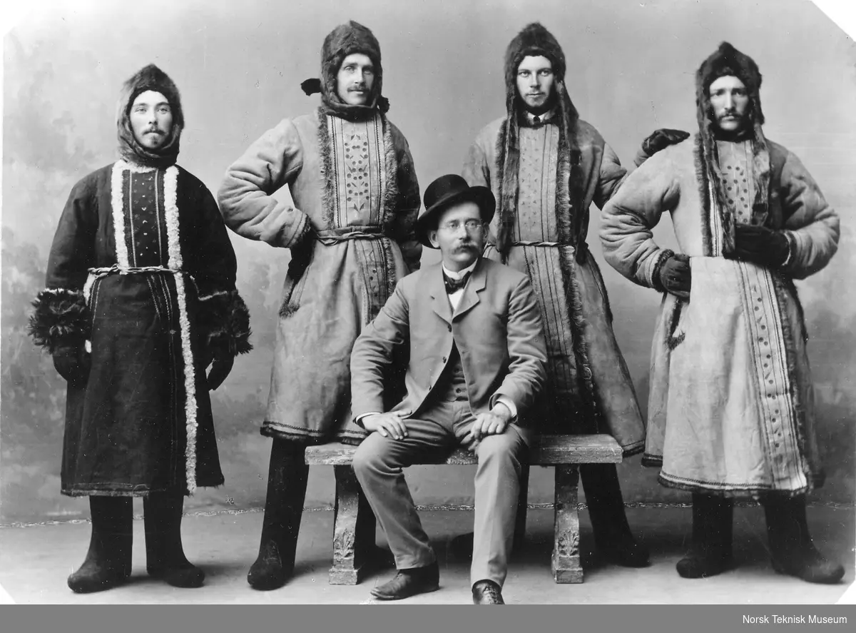 De videnskabelige samojeder paa Matoschkin Sckar [fire personer i karakteristisk skinnbekledning stående bak en sittende Kristian Birkeland]