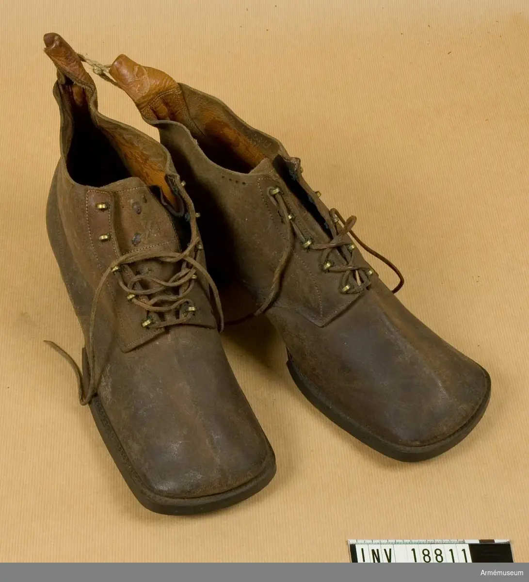 Av grovt, brunt läder med inskärning på framsidan och med 5 par hakar för att snöra skorna. Sulan betäckt med spikar och klacken med järnbeslag. På sulan finns nummer "4", på kängans innersida finns stämplar "78" - med krona ovanpå (möjligen år 1878). Andra stämplar oläsliga.