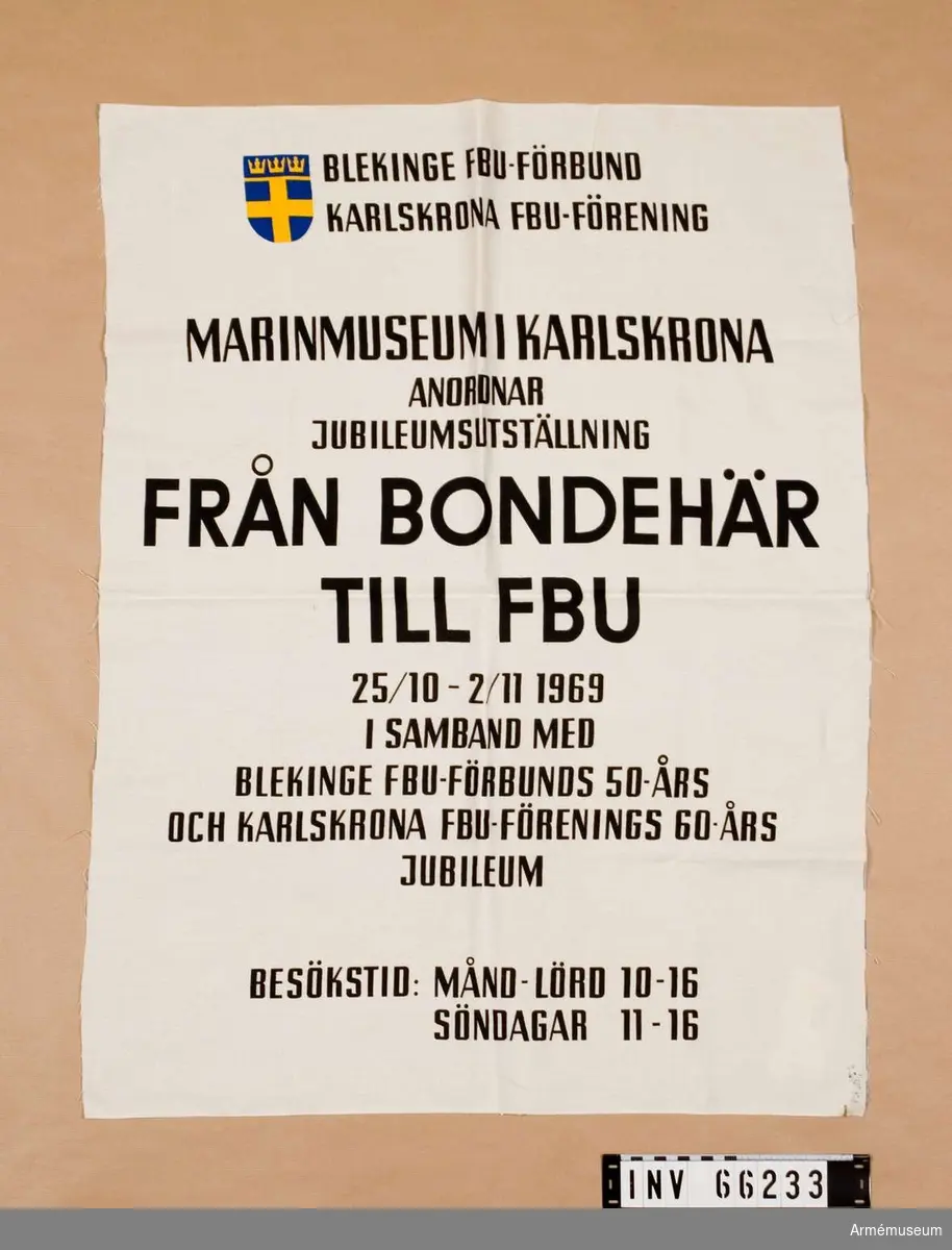 Grupp M I. 
Affisch tryckt på vit textil. "FRÅN BONDEHÄR TLL FBU" - jubileumsutställning 1969 vid Marinmuseum.