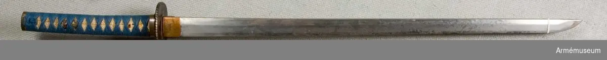 Eggad klinga av stål med fäste av en mångfald olika material (trä, järn, kopparlegering, hajskinn och silke). Har parerplåt (tsuba) av järn. 