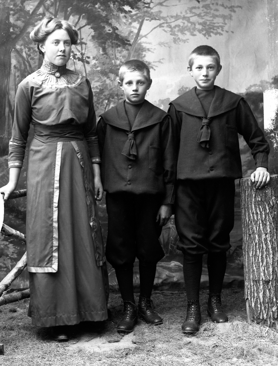 Gruppfoto av en ung kvinna och två pojkar i en ateljé.