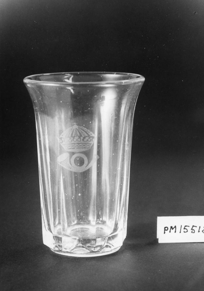 Dricksglas av ofärgat glas, åttkantigt, men runt upptill. På sidan ett krönt posthorn av 1912 års modell.