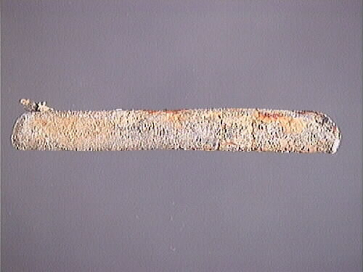 Sänke av bly.
Sänket består av en blybit som vikts runt en garntråd. Inuti sänket fins kvarsittande tråd. Sänkets yta är matt och fläckad av rostfärgade utfällningar.