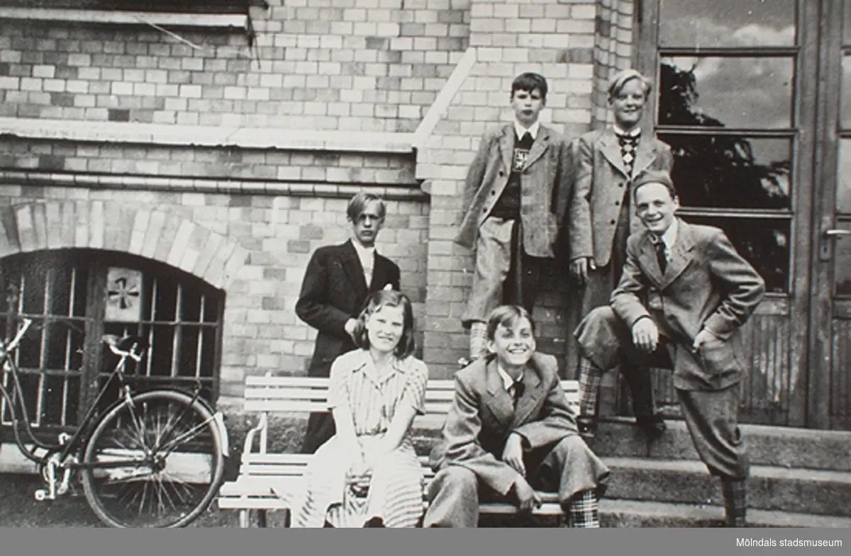 Fem pojkar och en flicka sitter eller står framför stora skolan på Stretereds skolhem. Okända personer och årtal.