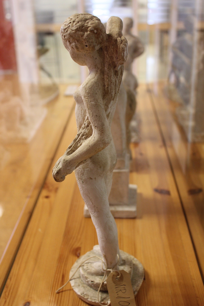 Skulptur i gips av en ung kvinne som tørker seg på ryggen med håndklær.