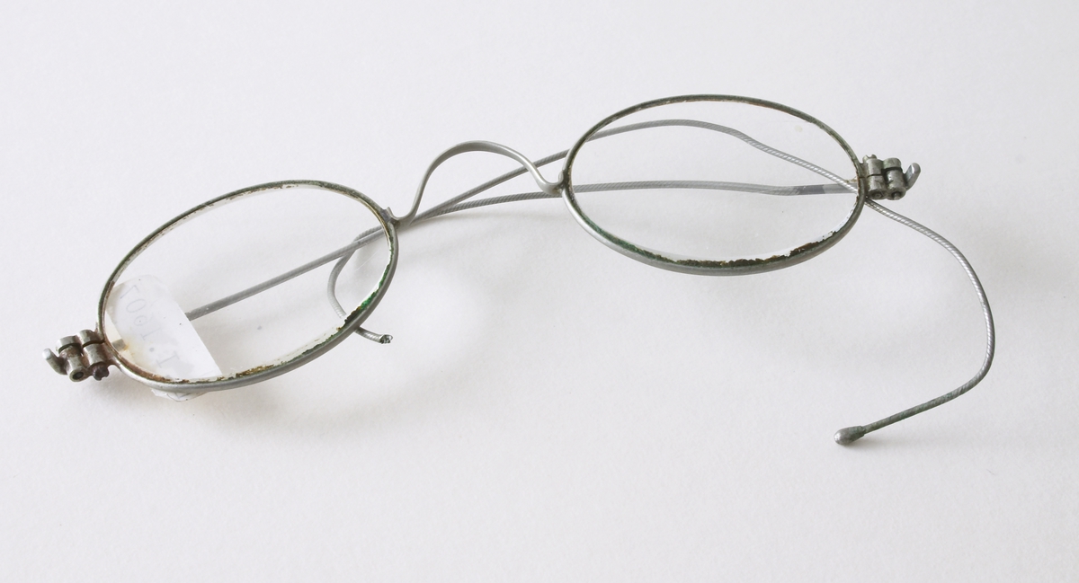 Et par gamle briller. Brukes til å lese eller se bedre. Små ovale glass - innfattet i sølv/stål ramme og stang.Den venstre stangen noe defekt. 