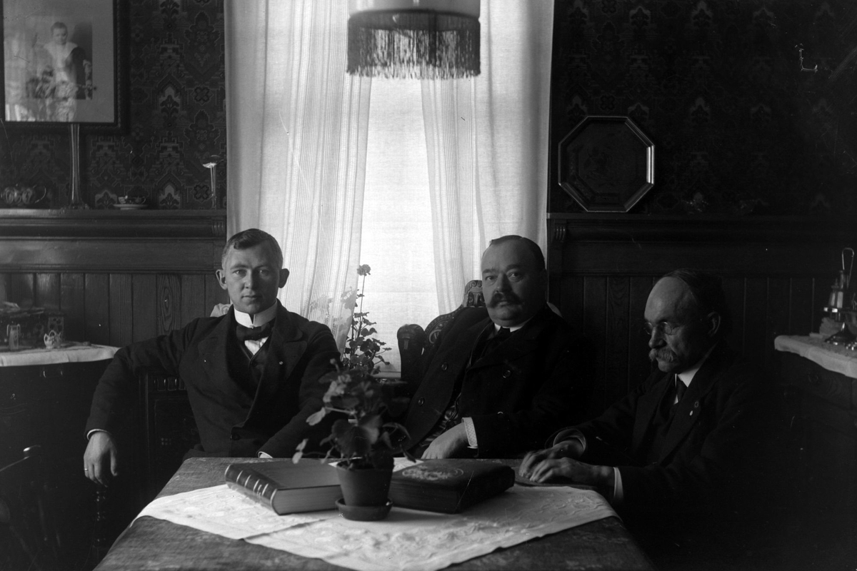 Tre menn rundt et stuebord.