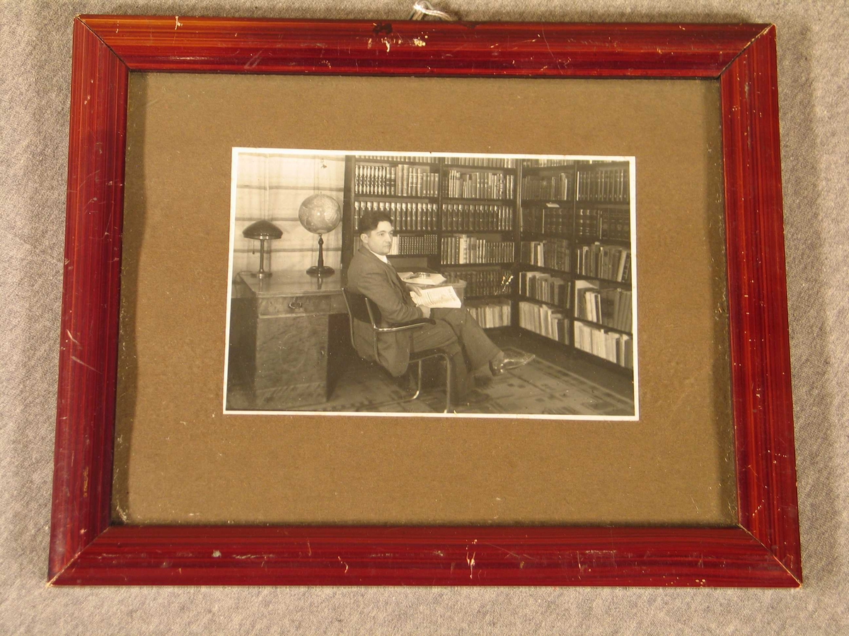 Dr Anders Øye i Naustdal sit på kontoret/biblioteket sitt. Builetet er innråma med grå pas partout og ei enkel brun treråme.