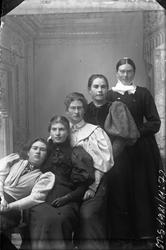 Atelierfoto av fem kvinner som står på rad. Den bakerste kvi