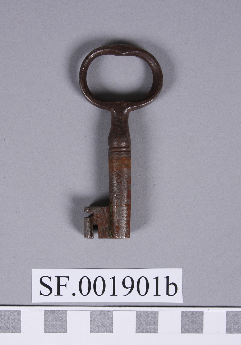 Nøkkel av jarn, med oval handdel. Nøkkelen sit fast i låsen.
