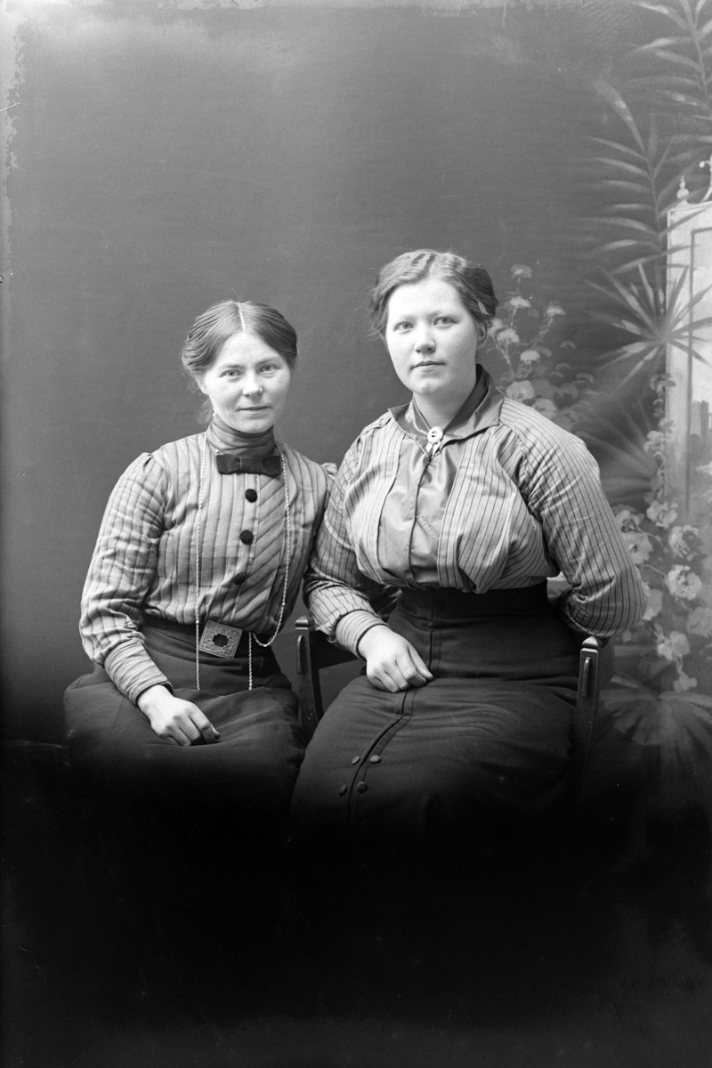 Studioportrett av to sittende kvinner.