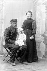 Studioportrett av en kvinne og mann med et barn på fanget.