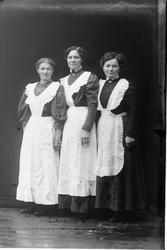 Studioportrett av tre kvinner med hvite forklær.