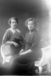 Studioportrett to kvinner sittende på en benk.