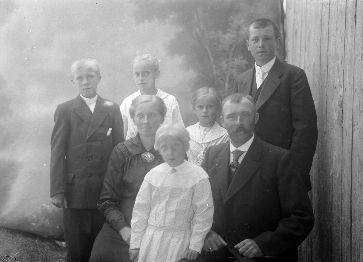 Studioportrett av en familie på syv i halvfigur, muligens familien Hellevik.