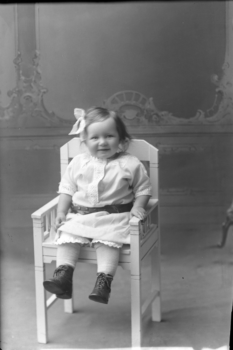 Studioportrett av et barn som sitter i en stol.