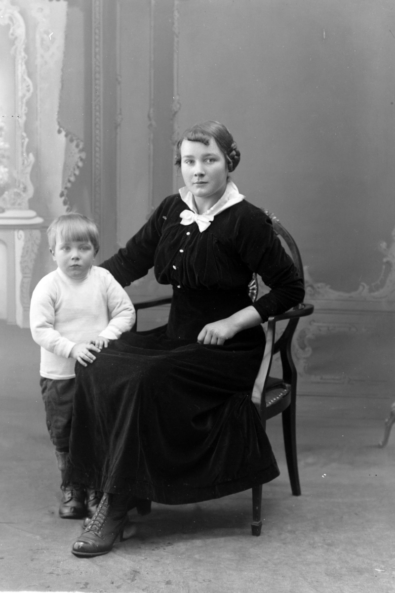 Studioportrett av en sittende kvinne med et barn.