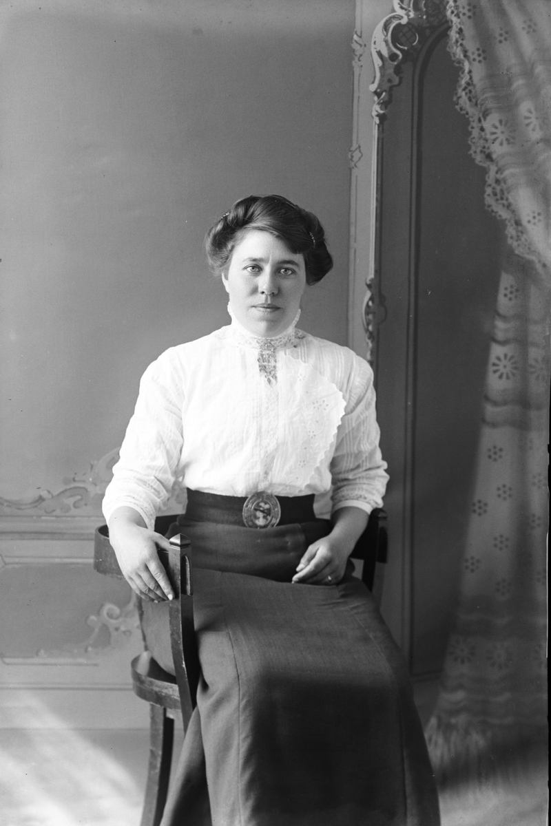 Studioportrett av en kvinne som sitter.