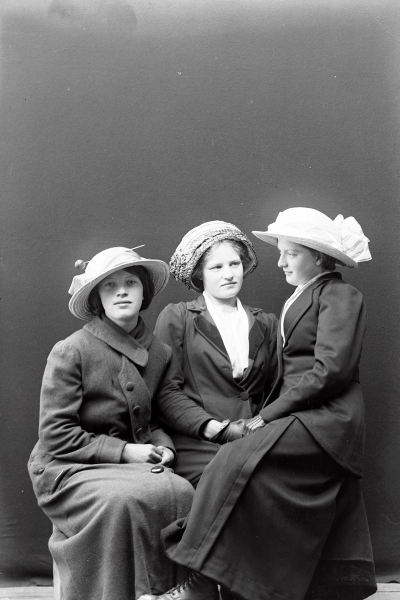 Studioportrett av tre sittende kvinner.