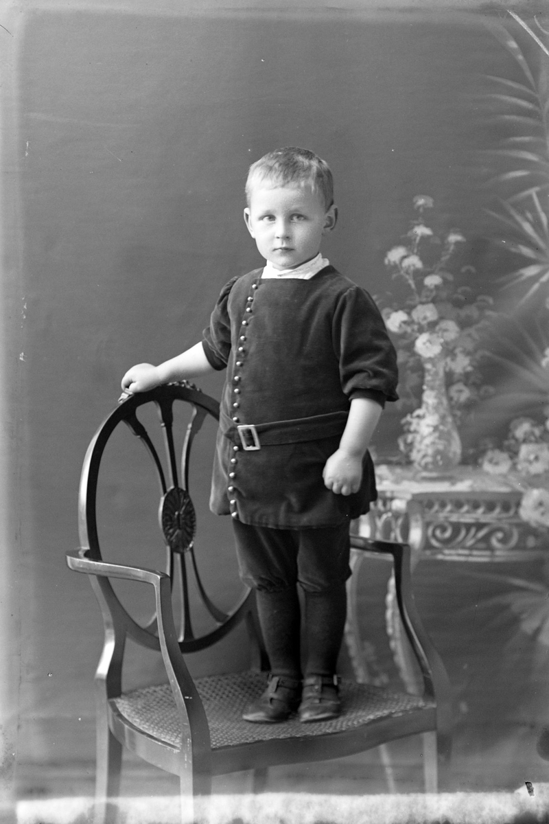 Studioportrett av et barn stående på en stol.