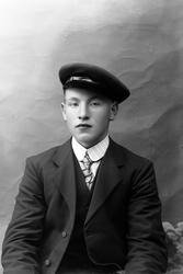 Studioportrett av en ung mann med lue på hodet.