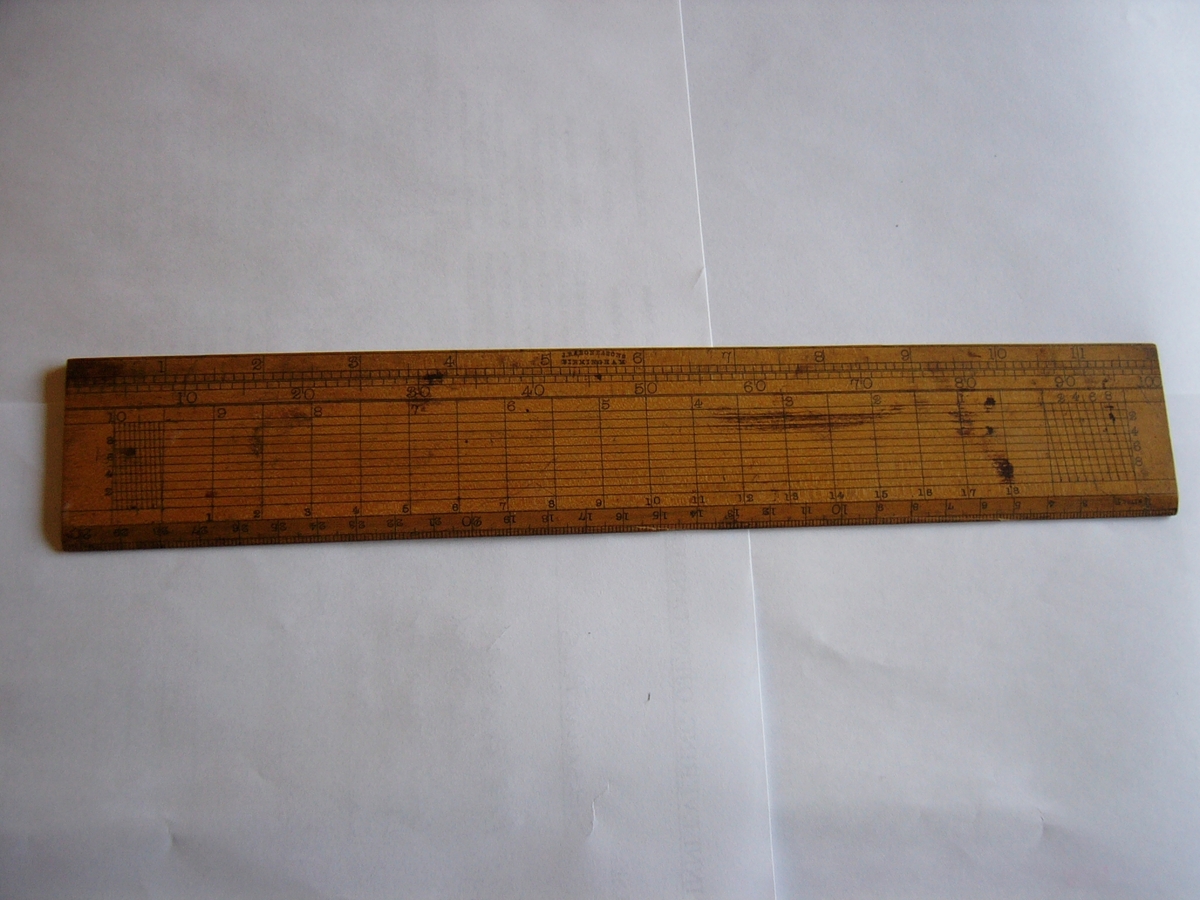 En 35 cm. lang linjal av tre med mange skalaer for avlesing.
