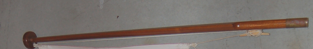 Elipseformet trestang med kule på toppen, og en rørformet messingholk i andre enden.