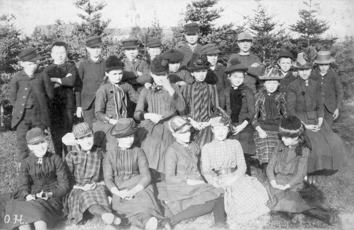 Gruppebilde - Middelskolen i Haugesund i 1891. Bildet er tatt i lotheparken, med Skåre kirke i bakgrunnen