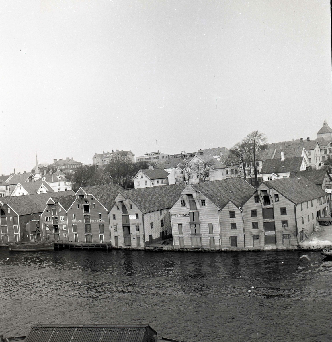 Sjøhusrekke på fastlandssiden i Haugesund, mello0m Åsvbygt. og Knut Knutsen OAS gt. Fotografert fra Trosnaberg på Risøy.