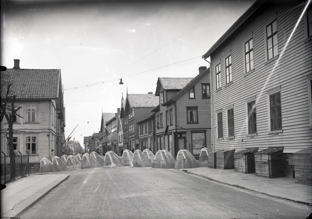 Veisperring med Hitlertenner i Strandgt. Huset til høyre er Haugesund trygdekasse (Strandgt. 99), med kasser spikret foran kjellervinduene. Fotografert fra sør mot nord.