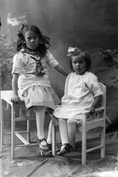 Studioportrett av to unge piker i helfigur.