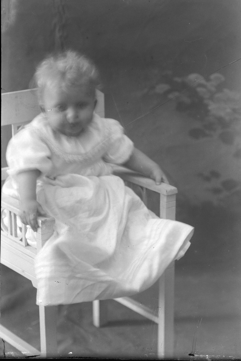 Studioportrett av et lite barn som sitter på en stol.