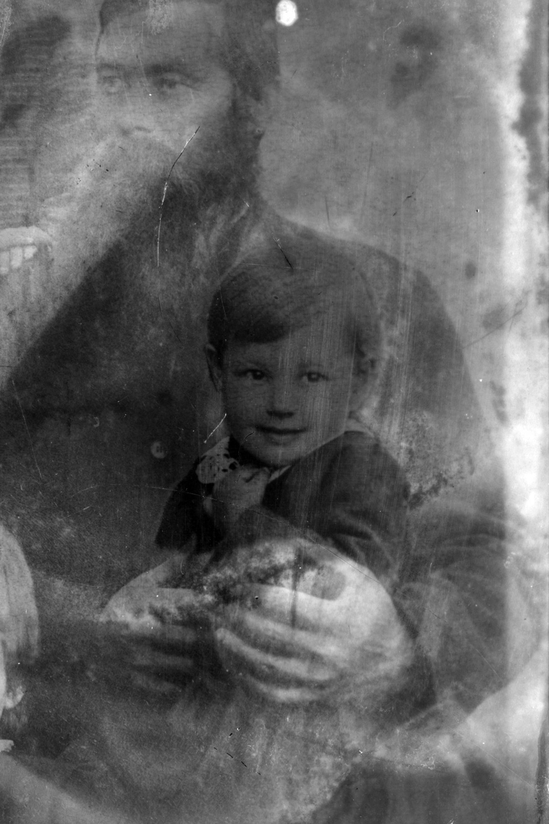 Studioportrett av et barn som sitter på en manns fang.