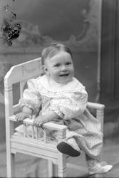 Studioportrett av et lite barn som sitter på en stol.