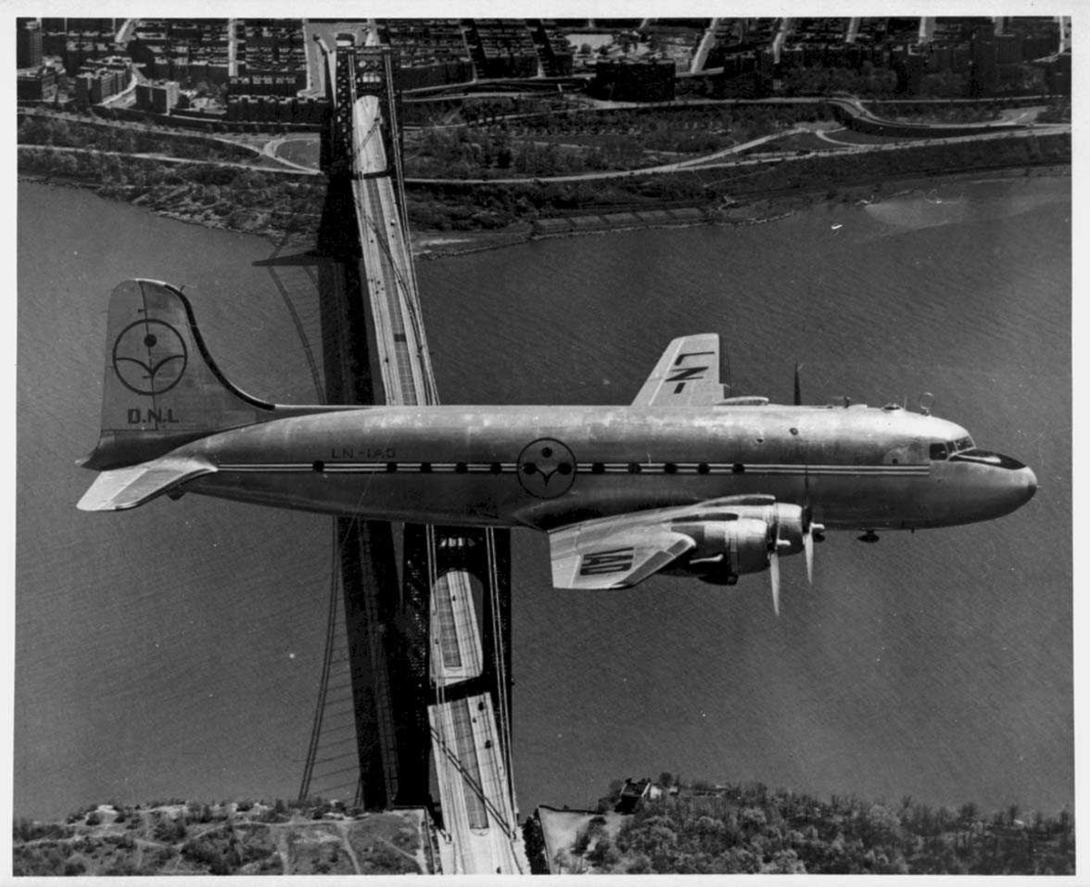 Ett fly i lufta, DC-4, LN-IAD fra DNL. Ei bru og bebyggelse under.