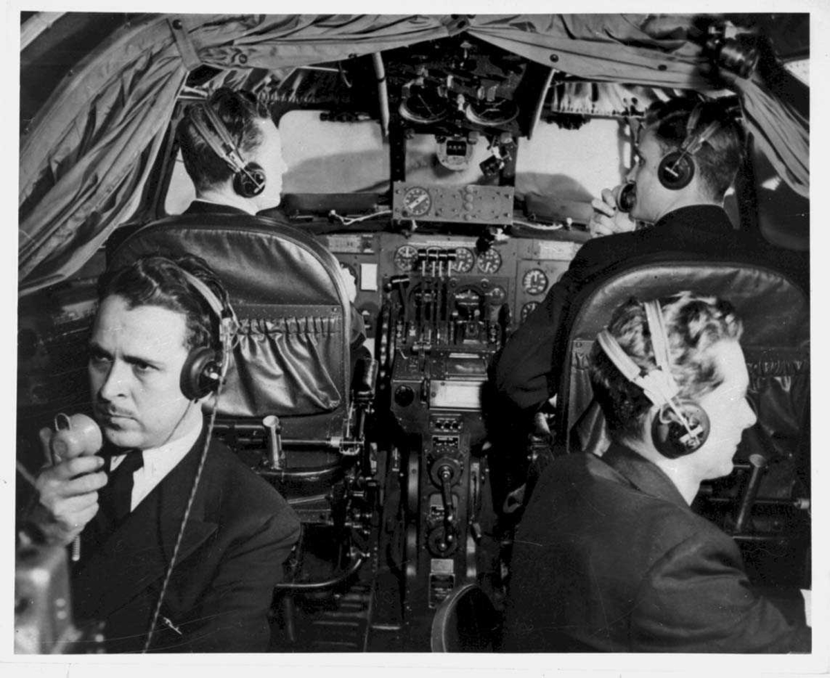 Fra cockpiten til en Boeing 314 Clipper. Tre personer, menn, i cockpiten.