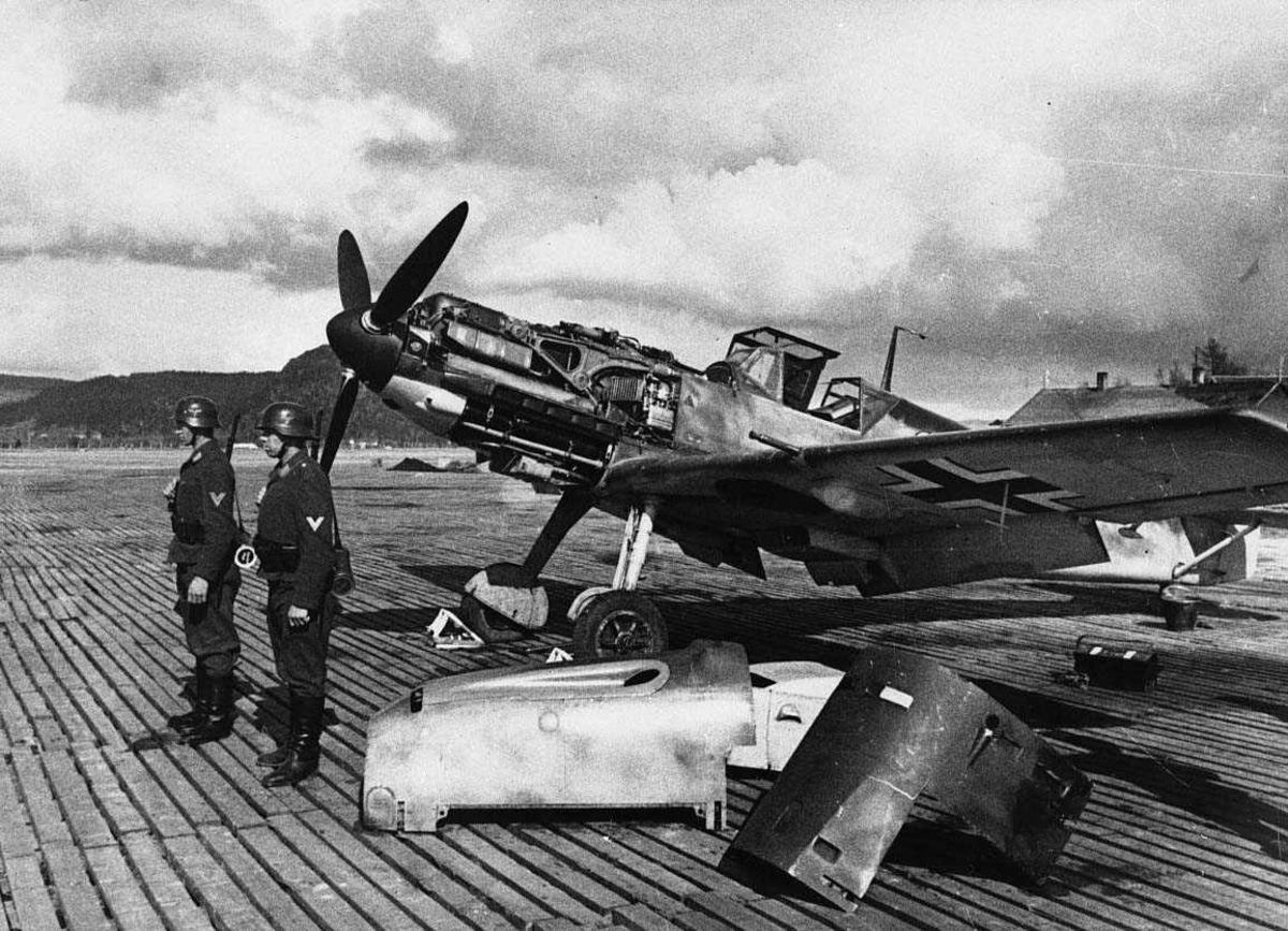 Lufthavn. tysk militert fly på bakken, Bf109. To vaktsoldater ved flyet.